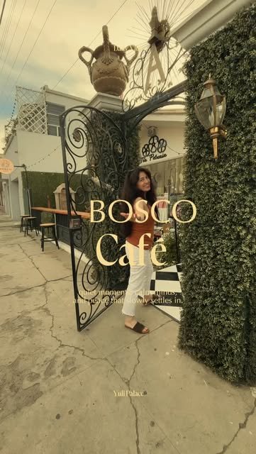 Entrada de Bosco Café con reja de herrería, muro de hiedra y piso de ajedrez