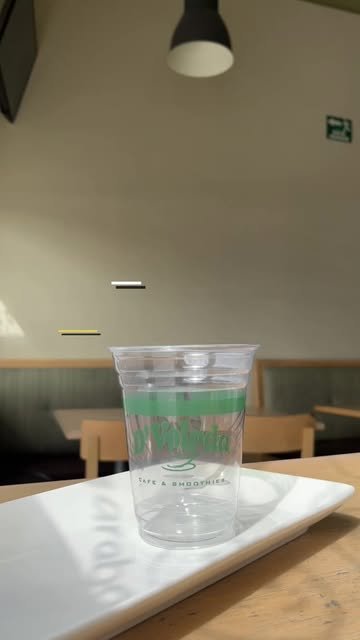 Vaso transparente de D'Volada con logo verde sobre una charola blanca en la sucursal