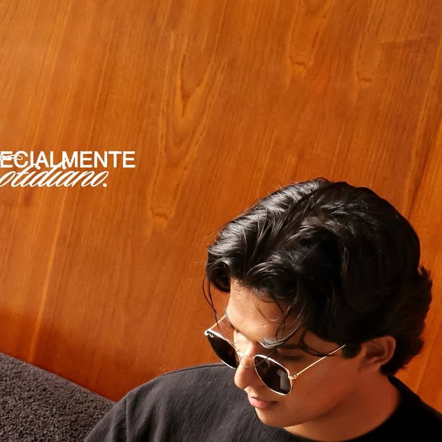 Chico con lentes de sol frente a la pared de madera de EMAÚS