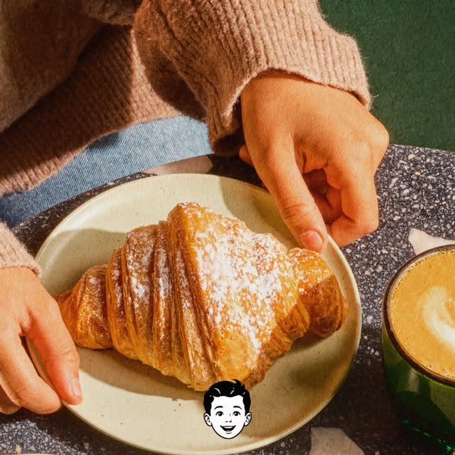 Croissant con azúcar glass junto a un latte