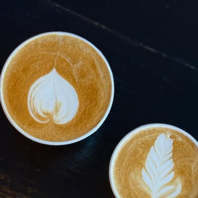 Dos lattes calientes con arte de corazón y hoja