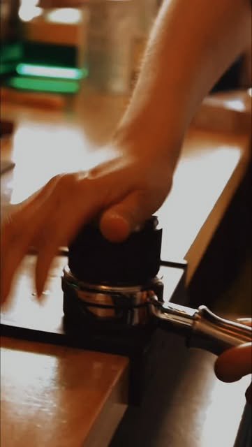 Barista apisonando el café en el portafiltro sobre la barra