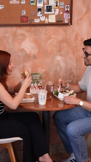 Pareja comiendo sándwiches en una mesa de Palta
