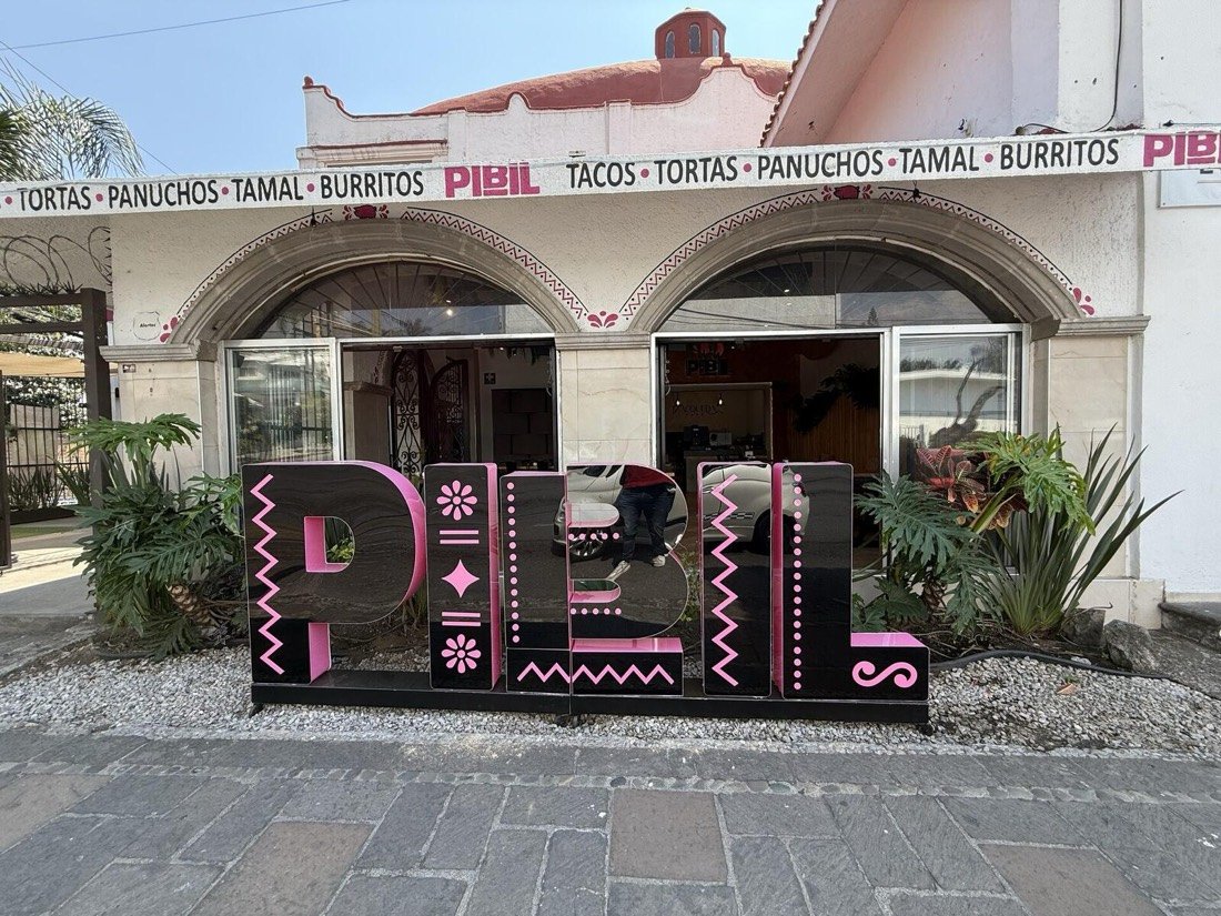 Fachada de Pibil con letras rosas bajo las arcadas
