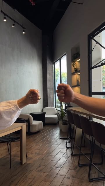 Dos manos jugando piedra, papel o tijera dentro del café