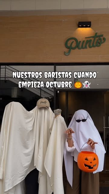 Baristas disfrazados de fantasmas frente al letrero de Punto