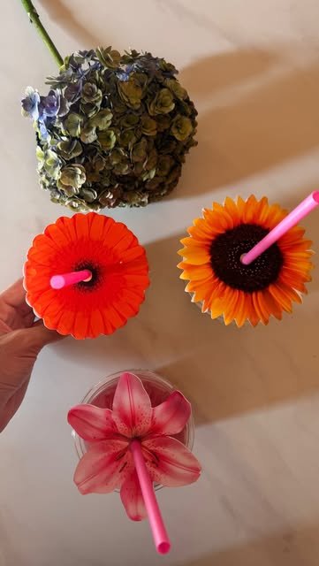 Tres bebidas de temporada vistas desde arriba, coronadas con gerbera naranja, girasol y lirio rosa