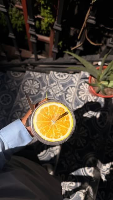 Bebida con una rodaja de naranja vista desde arriba sobre el piso de azulejo azul de la terraza