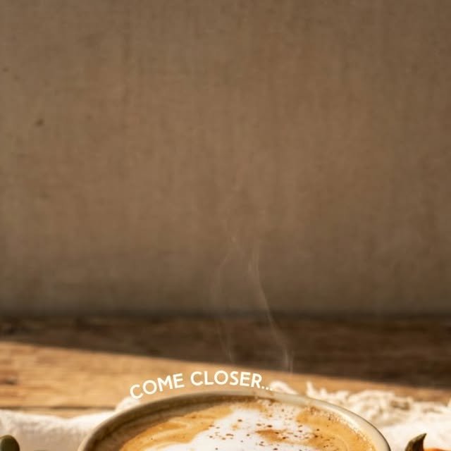 Latte con arte de espuma y vapor saliendo de la taza, sobre una mesa de madera