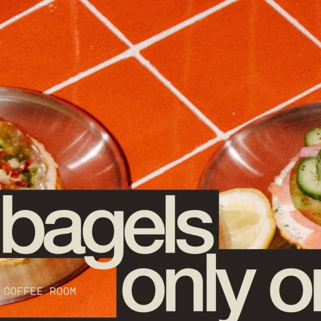 Dos bagels sobre platos de vidrio en mesa de azulejo naranja, con salmón, pepino y limón